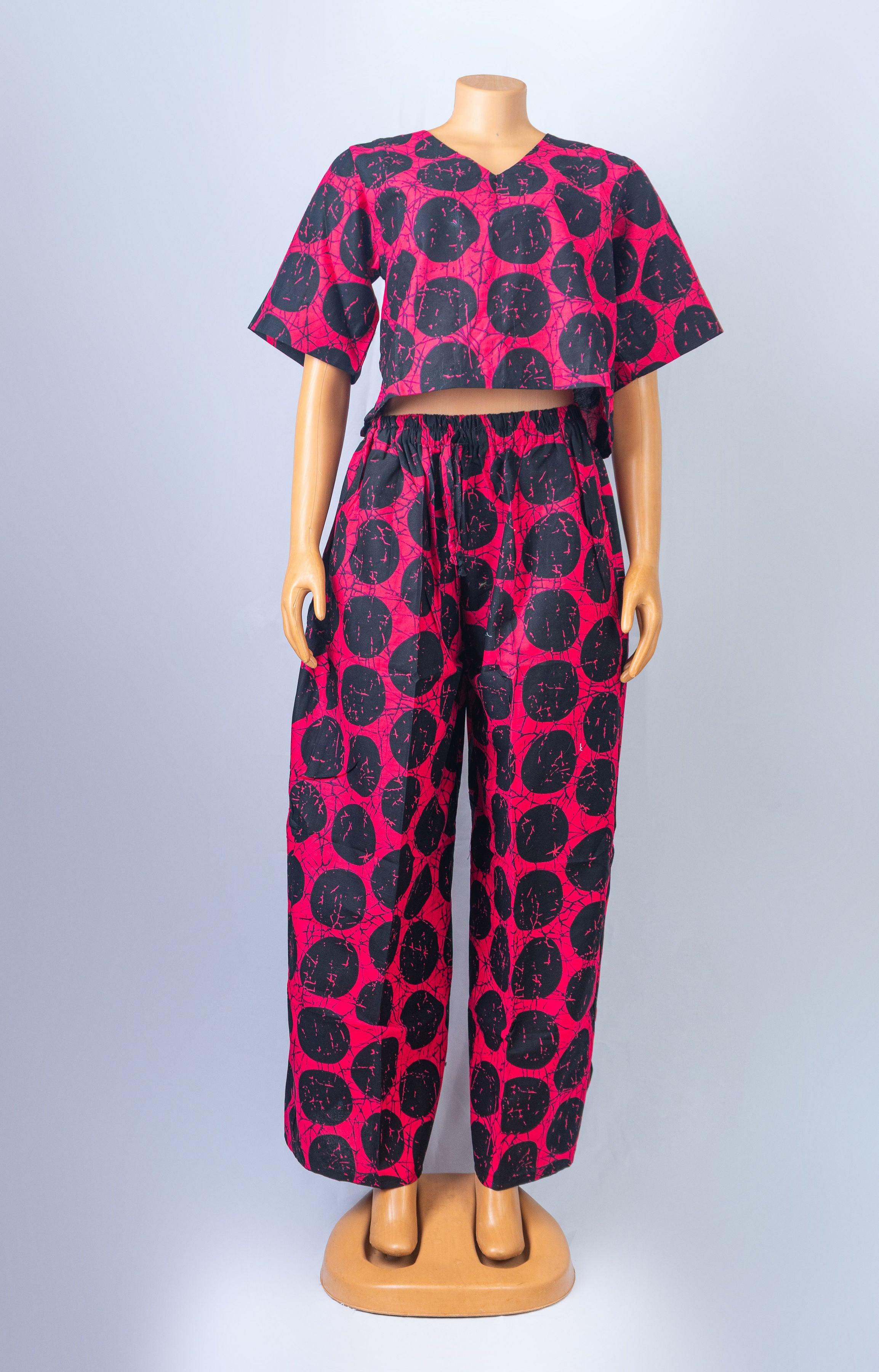 Mannequin wearing a vibrant red and black polka dot two-piece set, featuring a crop top and matching wide-leg pants.