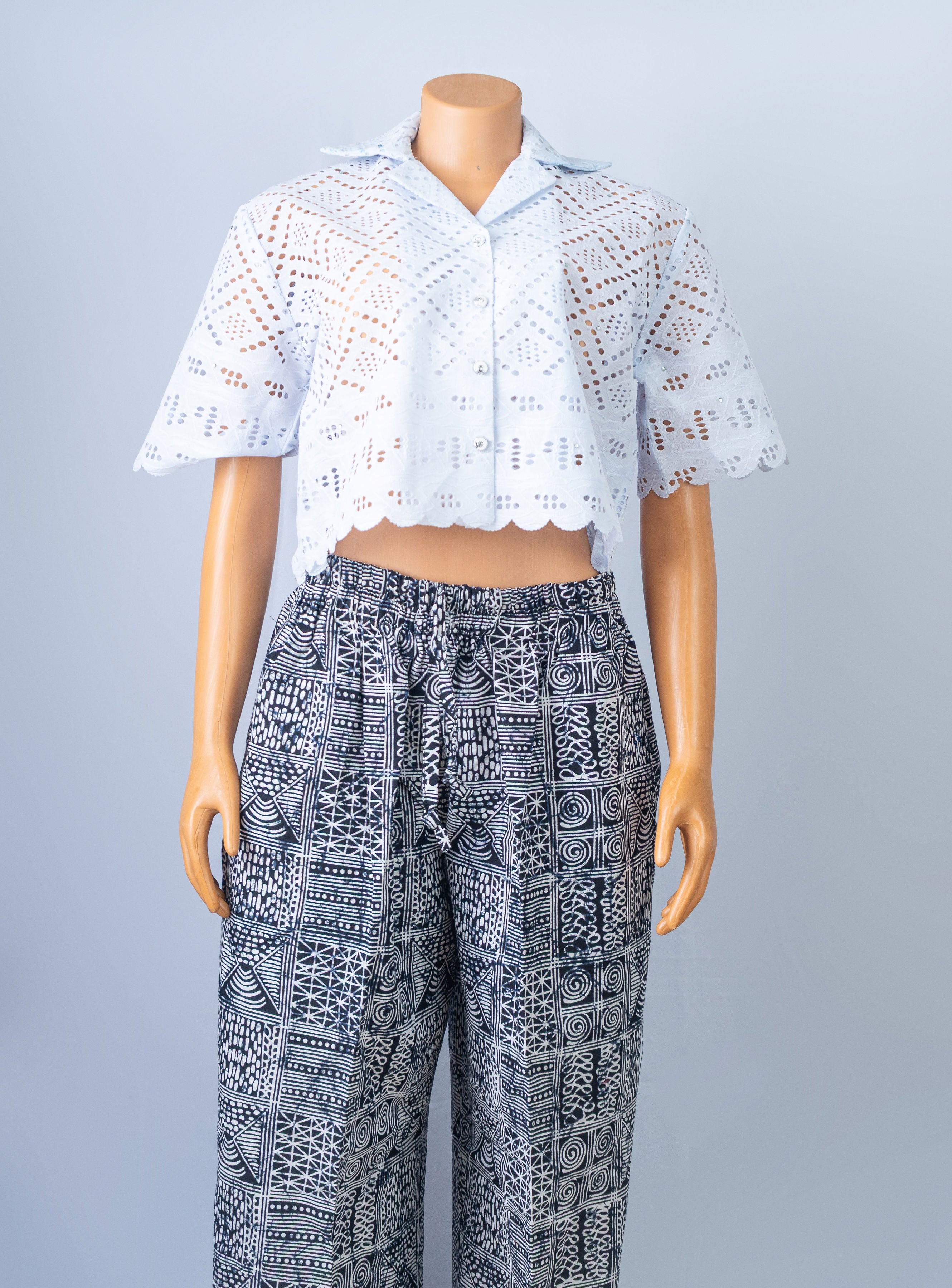 Mannequin wearing a white eyelet short-sleeve crop top with a scalloped hem and black and white patterned drawstring lounge pants.